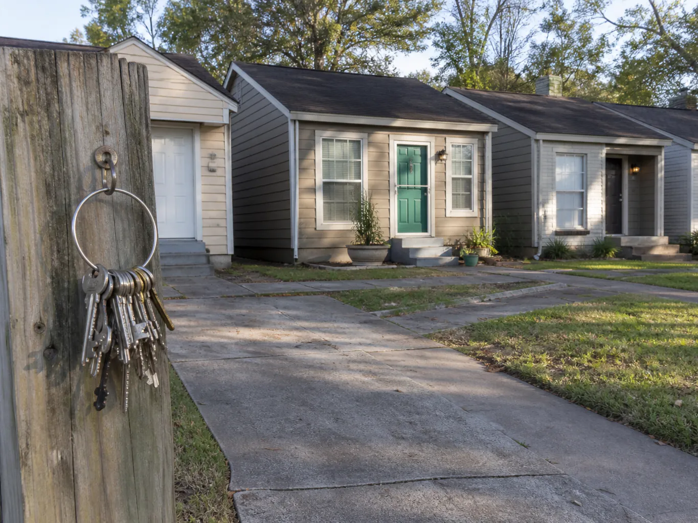 A row of small rental houses on one street with a ring of keys hanging on the fence post out front